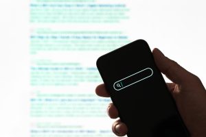 A hand holding a smartphone showing a blurred web search screen, highlighting digital search evolution.